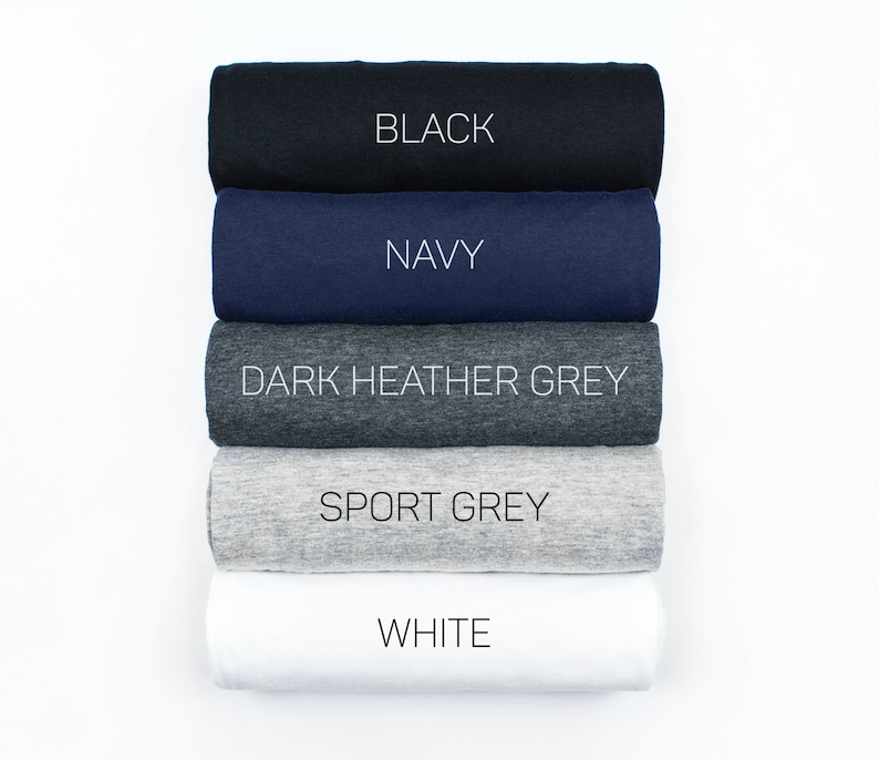 Puede incluir: Cinco camisetas enrolladas en diferentes colores: negro, azul marino, gris oscuro jaspeado, gris deportivo y blanco. Los colores est&aacute;n etiquetados en cada camiseta.