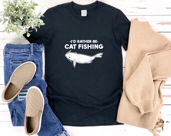 May include: Black t-shirt with white text that reads "I'd rather be cat fishing" and a white illustration of a catfish.