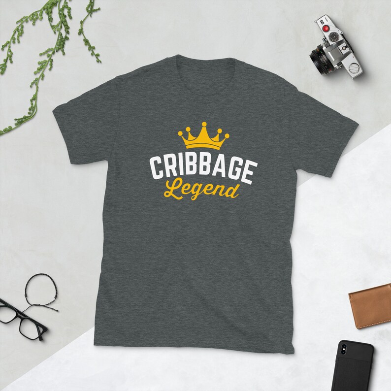 May include: A dark heather grey t-shirt with a white crown and the text "Cribbage Legend" in white.