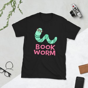 Peut inclure: T-shirt noir avec un ver vert portant des lunettes rouges et le texte "BOOK WORM" en rose.