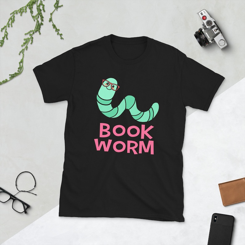 Peut inclure: T-shirt noir avec un ver vert portant des lunettes rouges et le texte "BOOK WORM" en rose.