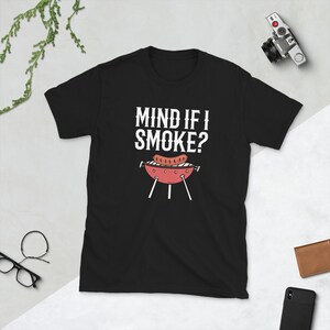 May include: Black t-shirt with white text that reads "Mind if I smoke?" and a cartoon image of a grill with a sausage on it.
