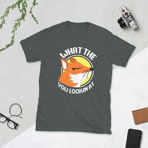 K&ouml;nnte beinhalten: Ein dunkelgraues T-Shirt mit einem Cartoon-Fuchsgesicht und dem Text "What the you lookin at".
