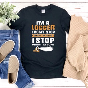 以下が含まれることがあります： チェーンソーのグラフィックと「I'm a Logger I don't stop when I'm tired I stop when I'm done」というテキストが書かれた黒いTシャツ。