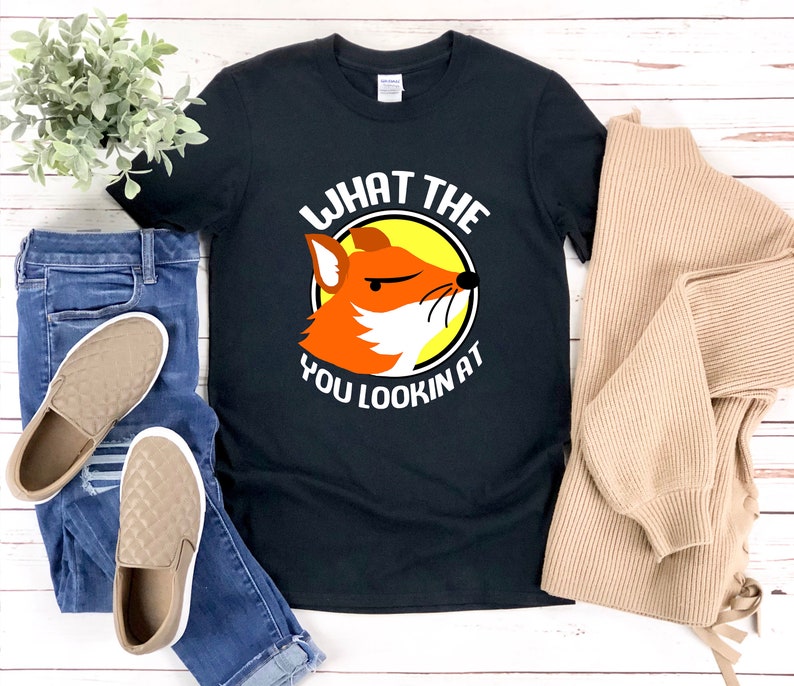 K&ouml;nnte beinhalten: Schwarzes T-Shirt mit einem Grafikdruck eines Fuchses mit dem Text "What the you lookin at" in Wei&szlig;.