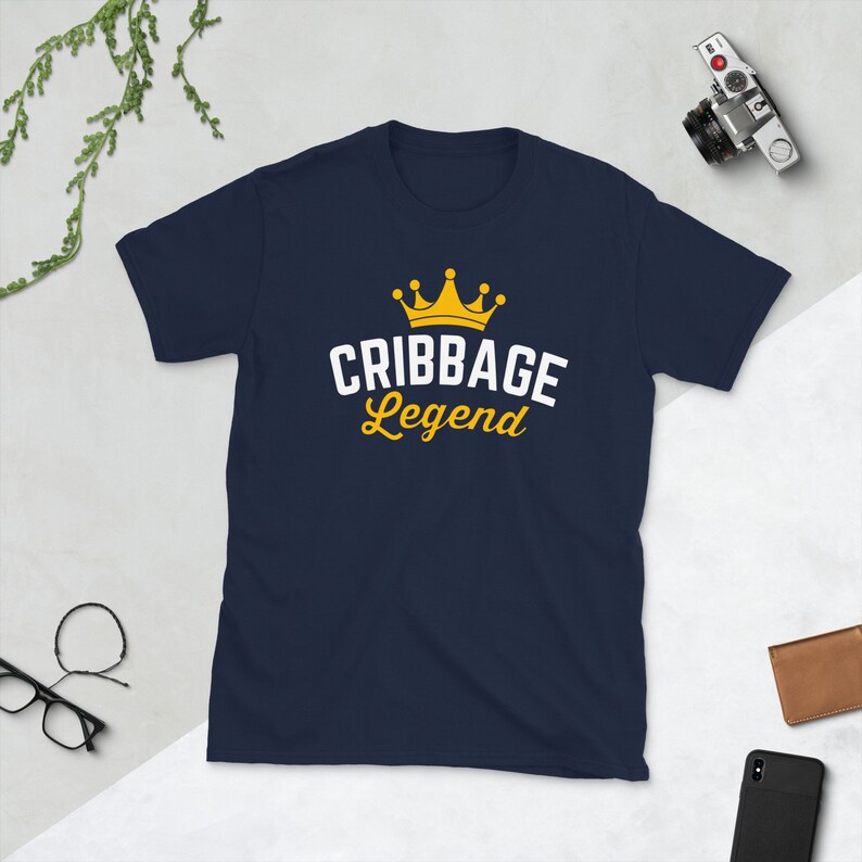 May include: A navy blue t-shirt with a white crown and the text "Cribbage Legend" in white and yellow.