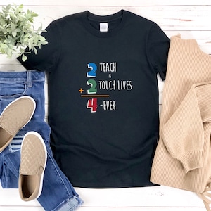 May include: Black t-shirt with a white graphic that says "2 Teach is 2 Touch Lives + 4 Ever".