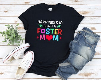 May include: Black t-shirt with the text "Happiness is being a Foster Mom" in rainbow colors with a red heart.