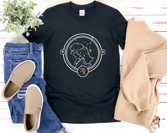Puede incluir: Camiseta negra con un gráfico blanco del signo del zodíaco Virgo. El gráfico presenta una imagen estilizada de la cabeza de una mujer con estrellas y el símbolo de Virgo.