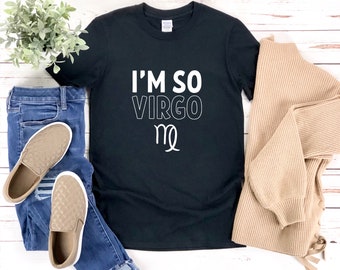 以下が含まれることがあります： 白い文字で「I'm So Virgo」と書いてある黒いTシャツと、乙女座の星座のシンボル。