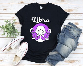 May include: Black t-shirt with a purple circle and white Libra zodiac symbol. The text "Libra" is written in white cursive letters above the symbol.