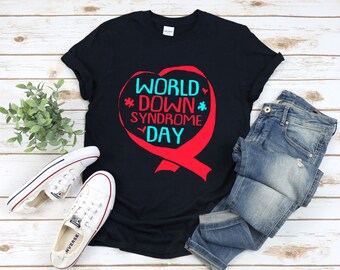 Puede incluir: Camiseta negra con un diseño de corazón rojo que dice "World Down Syndrome Day" en texto blanco y azul.