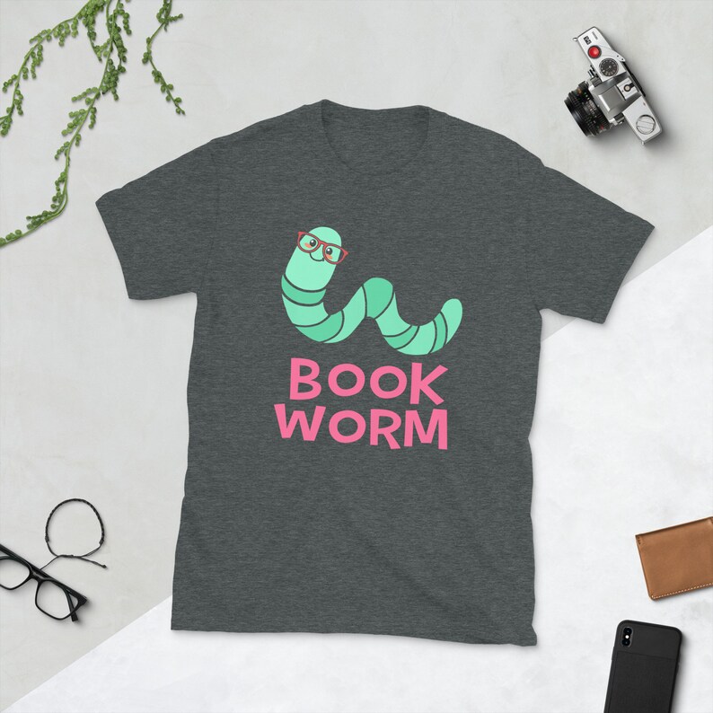 Peut inclure: Un t-shirt gris fonc&eacute; chin&eacute; avec un ver vert portant des lunettes rouges et le texte "BOOK WORM" en rose.