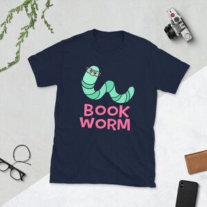 Peut inclure: T-shirt bleu marine avec un ver vert portant des lunettes roses et le texte "BOOK WORM" en rose.