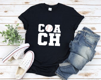 May include: A black t-shirt with white text that reads "COACH" with a baseball graphic in the center of the word.