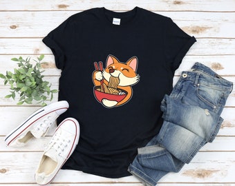 May include: A black t-shirt with a cartoon image of a dog eating ramen noodles from a bowl. The dog is orange and white with a happy expression.