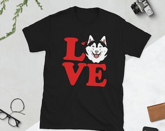 May include: Black t-shirt featuring the word "LOVE" in red block letters and a smiling husky dog graphic. The dog has black and white fur and is positioned above the "VE". Two small red hearts are above the dog's head.