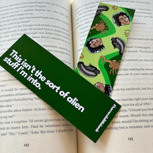 May include: Two green bookmarks with different designs. The bookmark on the left has white text that reads "This isn't the sort of alien stuff I'm into." The bookmark on the right has a repeating pattern of black and green alien creatures and the text "#horrorofalittlebook".