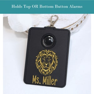 May include: Black leather key chain with a gold lion design and the name "Ms. Miller" embroidered on it. The keychain has a clear plastic window for a button.