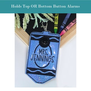 May include: A blue glitter crayon-shaped keychain with a black button and the text "MRS. JENNINGS" in black. The keychain is attached to a silver key ring.