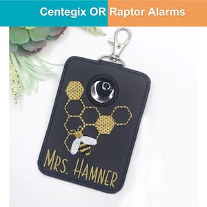 May include: Black rectangular keychain with a silver clasp. The keychain features a gold embroidered honeycomb design with a white and black bee. The text "MRS. HAMNER" is embroidered in gold. The top of the keychain has a silver-colored circle.