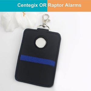 May include: Black rectangular key fob holder with a blue stripe and a silver clasp. The holder has a circular opening and the text "Centegix OR Raptor Alarms" at the top.