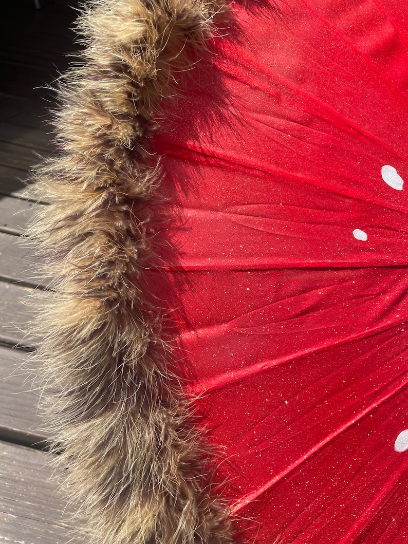 Pode incluir: Um close-up de um guarda-sol vermelho com acabamento em pele castanha e bolinhas brancas. O tecido do guarda-sol tem um acabamento brilhante e a borda de pele adiciona um toque de eleg&acirc;ncia. O design &eacute; atraente e &uacute;nico.