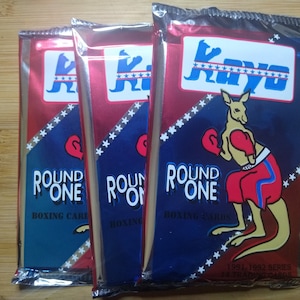 May include: Three unopened packs of Round One boxing cards featuring a red, white, and blue kangaroo wearing boxing gloves. The packs are labeled "Round One Boxing Cards" and "1991-1992 Series Trading Cards".