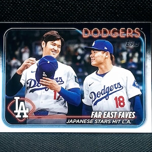 May include: A baseball card featuring two Los Angeles Dodgers players in white and blue uniforms. The card has the word "Dodgers" in red and the text "Far East Faves Japanese Stars Hit L.A."