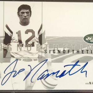 Puede incluir: Una tarjeta de intercambio en blanco y negro con Joe Namath, un ex mariscal de campo de fútbol americano, vistiendo un uniforme de los New York Jets. La tarjeta es de la serie "Sign of the Times" y presenta la firma de Namath.