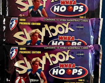 May include: Three packs of Skybox WNBA Hoops trading cards. Each pack contains 10 cards and features a different WNBA player on the front. The packs are purple and feature the text "Skybox WNBA Hoops" and "1999 Premiere Edition".