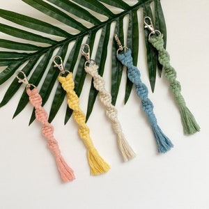Puede incluir: Cinco llaveros de macramé de colores con anillas de plata. Los llaveros son en tonos rosa, amarillo, crema, azul y verde.