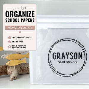 May include: A white memory box kit for organising school papers. The box features the name "GRAYSON" in a circular design, with the text "school memories" below. The kit includes a custom name label and 46 file tabs. The text "ORGANIZE SCHOOL PAPERS" is also visible.