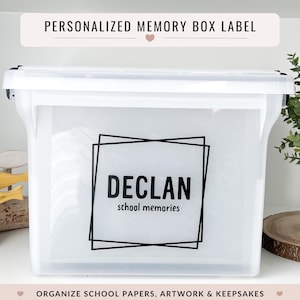 Peut inclure: Une boîte à souvenirs en plastique blanc avec une étiquette noire indiquant "DECLAN school memories". La boîte a un couvercle transparent et des loquets noirs. Le texte "PERSONALIZED MEMORY BOX LABEL" est en haut. Le texte "ORGANIZE SCHOOL PAPERS, ARTWORK & KEEPSAKES" est en bas.