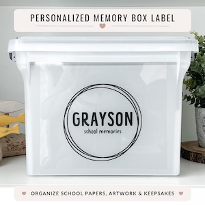 May include: A white plastic memory box with a lid, featuring a circular label with the name "GRAYSON" and "school memories." The box has a label at the top that says "PERSONALIZED MEMORY BOX LABEL." The bottom label says "ORGANIZE SCHOOL PAPERS, ARTWORK & KEEPSAKES."