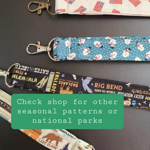 May include: Close-up of several lanyards with various patterns. One features American flags, another has snowmen on a blue background, and a third displays national park graphics. The text on the image says "Check shop for other seasonal patterns or national parks."