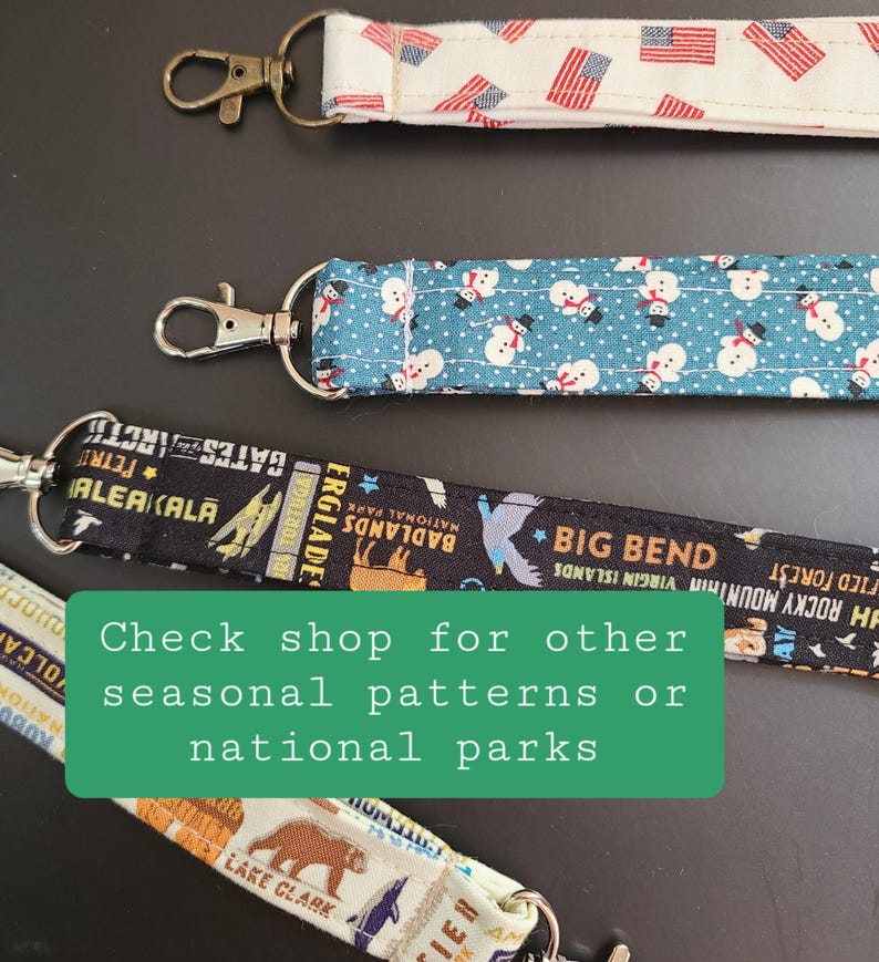 May include: Close-up of several lanyards with various patterns. One features American flags, another has snowmen on a blue background, and a third displays national park graphics. The text on the image says "Check shop for other seasonal patterns or national parks."