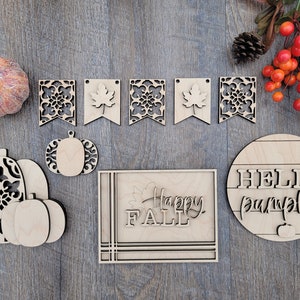 May include: A set of wooden fall-themed decorations, including a "Happy Fall" sign, a "Hello Pumpkin" sign, and a pumpkin banner with leaf and floral cutouts.