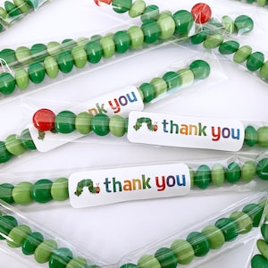 May include: Green candy beads strung together in a clear plastic bag with a "thank you" sticker featuring a caterpillar illustration.