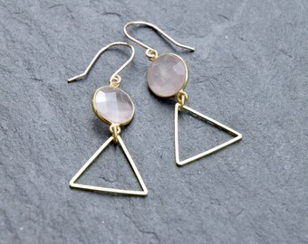 May include: A pair of gold earrings with pink gemstone accents and triangle shapes.