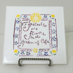 May include: White ceramic tile with a floral design and the quote "Friends are flowers in the garden of life." The tile features a border of purple, yellow, and blue flowers, and a yellow sun.