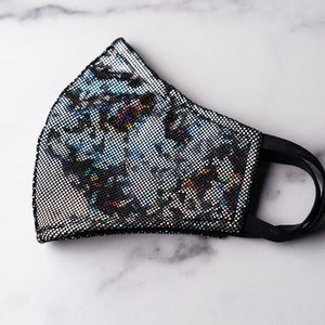 May include: A black face mask with a silver iridescent pattern. The mask has a black elastic band.