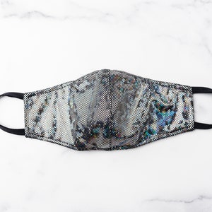 May include: A black and silver face mask with an iridescent pattern. The mask has a black elastic band.