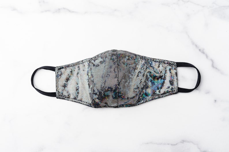 May include: A black and silver face mask with an iridescent pattern. The mask has a black elastic band.