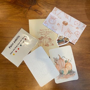 May include: A set of stationery items including a paint palette card with yellow, red, orange, green, blue, and brown paint dots, a card with the text Open for a Gourd-geous Surprise, a pumpkin-patterned envelope, a sticker, and two pumpkin cards.