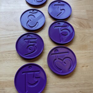 May include: Seven purple round coasters with different symbols, including the Om symbol, on a wooden surface.