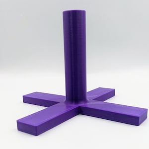 Op de afbeelding: Een paarse plastic standaard met een hoge, cilindrische paal en een kruisvormige basis.