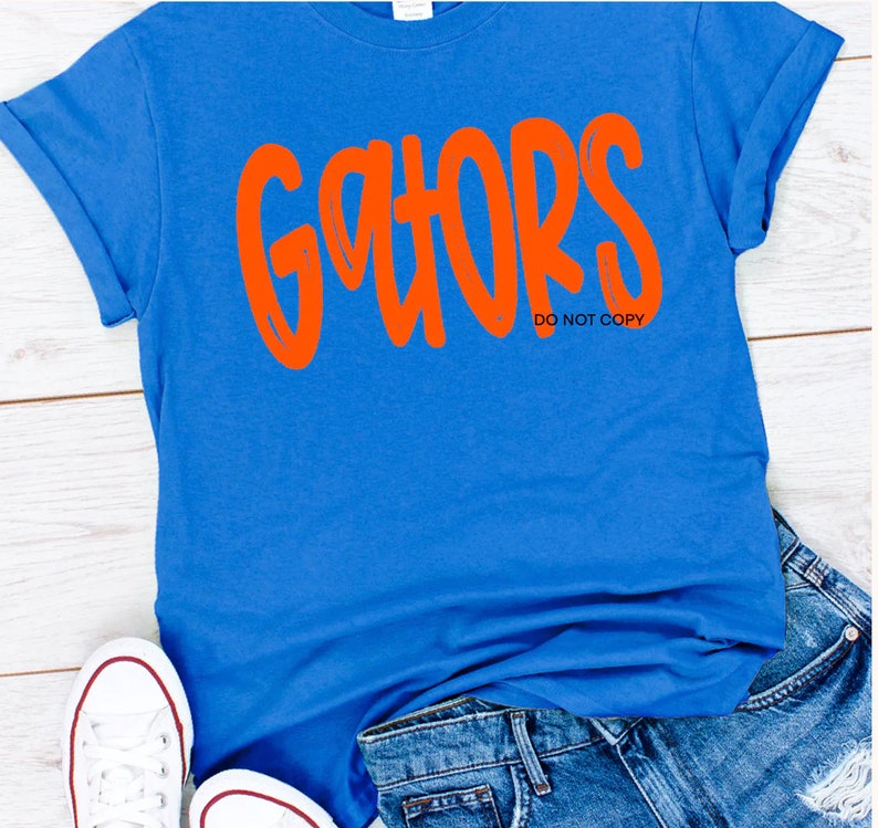 May include: A royal blue t-shirt with the word "gators" in orange lettering. The text "DO NOT COPY" is printed below the word "gators".