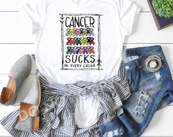 May include: White t-shirt with a graphic design that says "Cancer Sucks in Every Color". The graphic features a variety of colored ribbons.