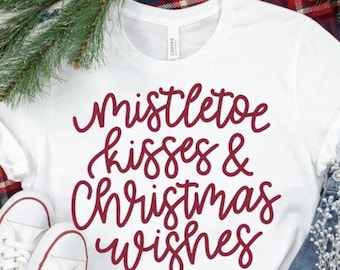 May include: White t-shirt with the text "Mistletoe kisses & Christmas wishes" in red cursive lettering.